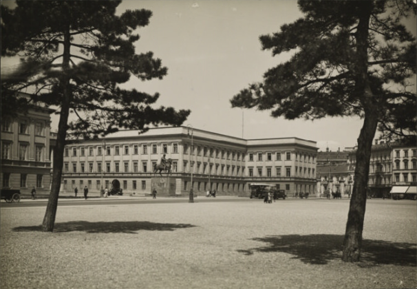 An old photo showing the Saski Palace. It is a neoclassicist, two floor building with two wings. The building faces the big, open space of Piłsudski Square.