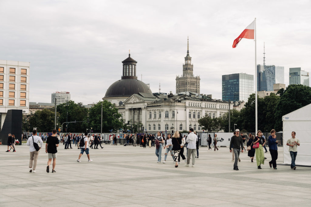 Widok na plac Piłsudskiego w Warszawie. Na ogrodzeniu wokół inwestycji odbudowy Pałacu Saskiego zawieszono plansze z wystawą Dom w ramach biennale. W tle zabudowania, w tym budynek Zachęty.
