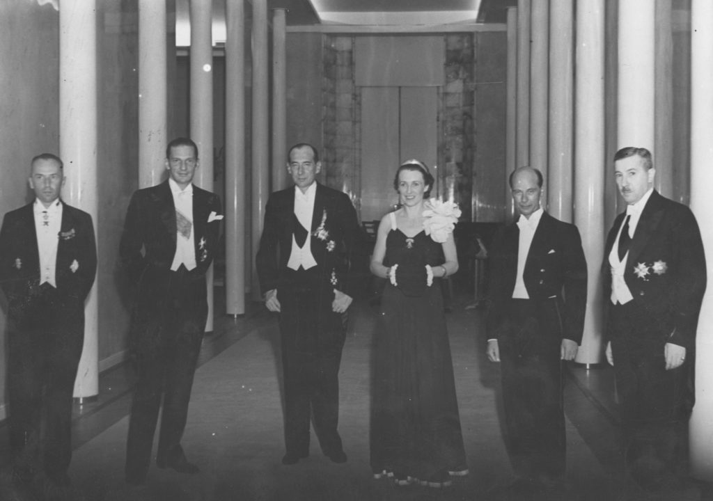 Jedna kobieta (Jadwiga Beck) i pięciu mężczyzn (wśród nich, obok Jadwigi, Józef Beck) na reprezentacyjnym korytarzu MSZ-u podczas wizyty kierownika szwedzkiego resortu spraw zagranicznych w Pałacu Bruhla, międzywojnie.