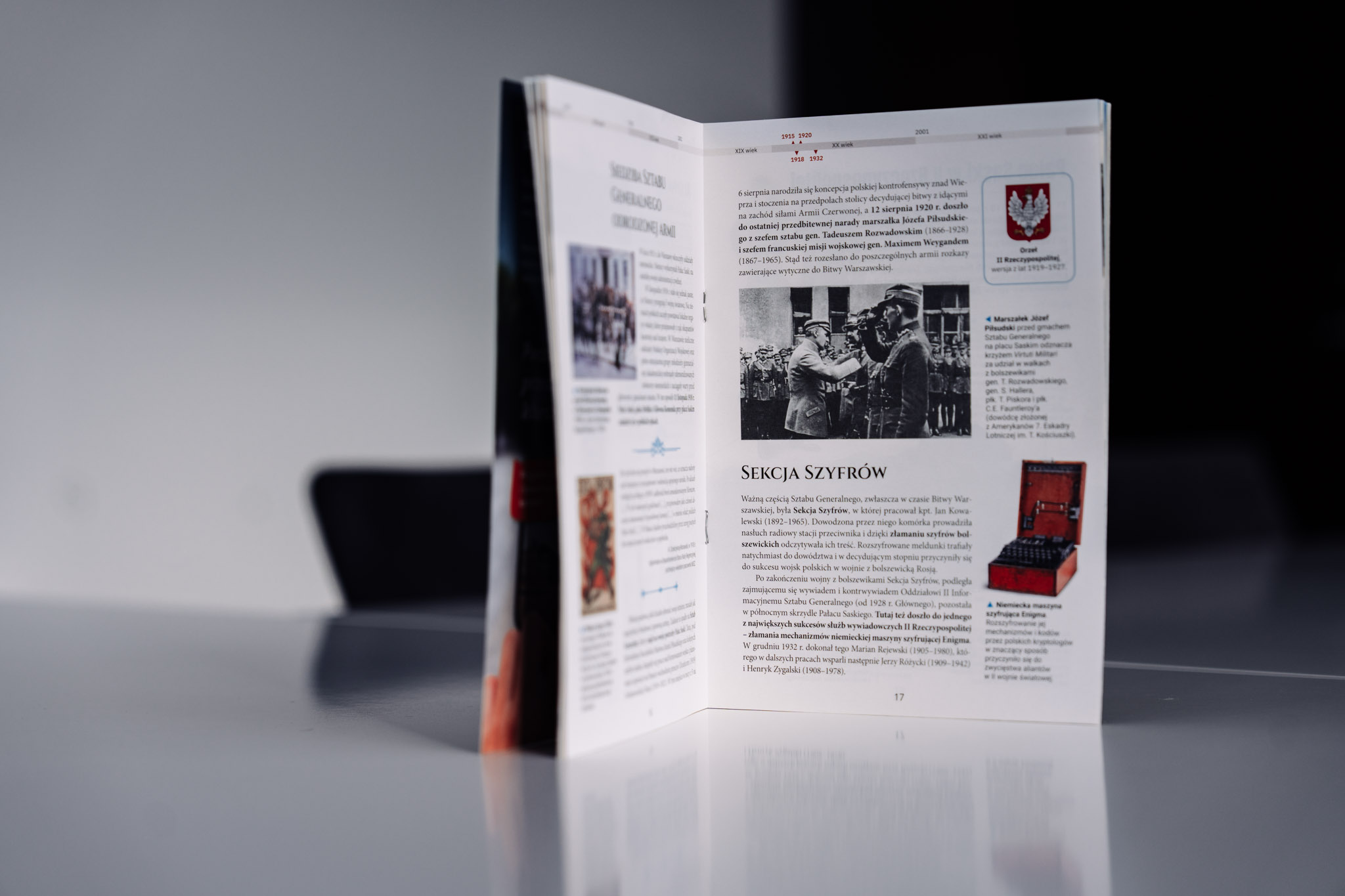Otwarta broszura edukacyjna Pałac Saski niezwykłe miejsce w niezwykłym mieście. Broszura stoi otwarta na stole, na stronie z nagłówkiem o sekcji szyfrów i zdjęciem Józefa Piłsudskiego wraz z wojskowymi.