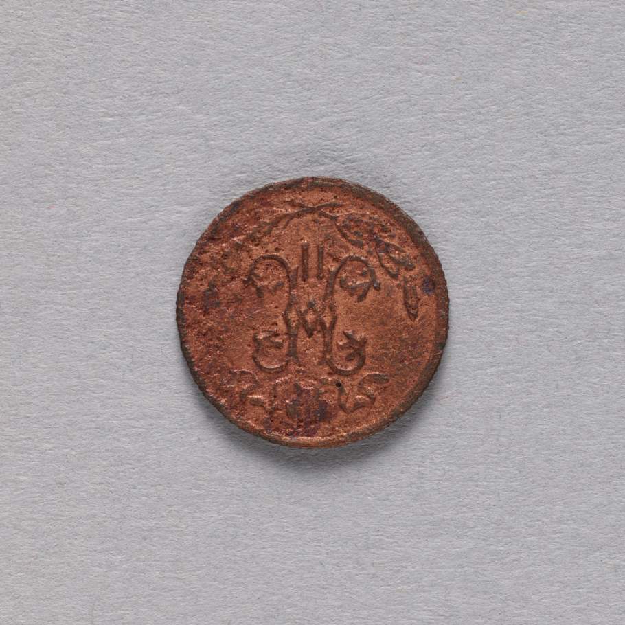 Metalowa moneta, barwa brązowo-miedziana. Zdobiona w górnej części dwoma skrzyżowanymi, rozchodzącymi się w przeciwnych kierunkach gałązkami. Na środku skrzyżowane zdobienia roślinne w lustrzanym odbiciu, wpisujące się w kształt litery "H".