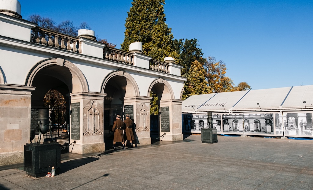 Grób Nieznanego Żołnierza w Warszawie, czyli cztery arkady, pod którymi znajduje się płyta nagrobna, do której zmierzają dwaj żołnierze. Obok budowli znajduje się ogrodzenie, na którym są archiwalne, przedwojenne zdjęcia Grobu, kiedy było więcej arkad, a nad wszystkim kolumnada Pałacu Saskiego.